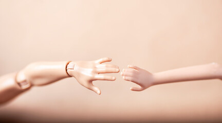Doll hands joining together on a blurred background.