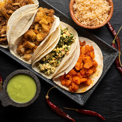 Different types of tacos also called guisados on a dark background. Mexican food