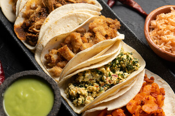 Different types of tacos also called guisados on a dark background. Mexican food