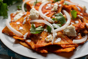 Mexican food. Red chilaquiles with cheese and sour cream on white background