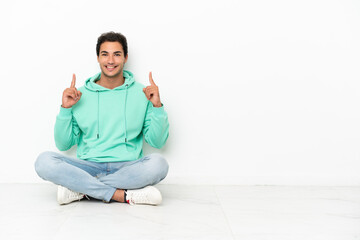 Caucasian handsome man sitting on the floor pointing up a great idea
