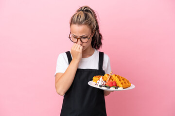 Restaurant waiter Russian girl holding waffles isolated on pink background having doubts