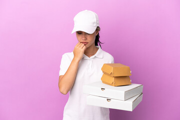 Pizza delivery Russian girl with work uniform picking up pizza boxes and burgers isolated on purple...