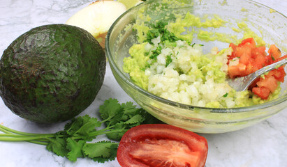 Ingredients to make guacamoles in a bowl before mixing 