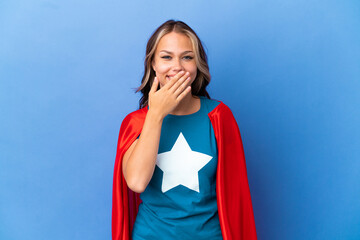 Super Hero Teenager girl isolated on blue background happy and smiling covering mouth with hand