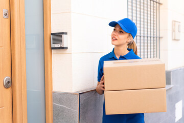 Young delivery woman at outdoors holding boxes