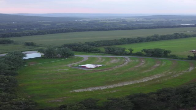 Empty drive-in movie theater in rural countryside with trees and fields at sunset. Vertical 4K aerial drone video.