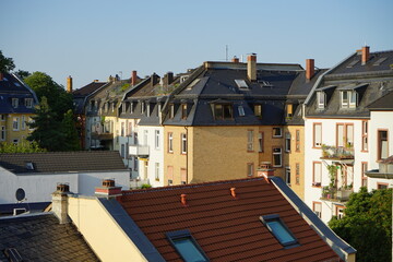Schöne restaurierte Fassaden von Altbauten in Pastelltönen und Naturfarben mit ausgebauten Dächern vor blauem Himmel im Sonnenschein im Nordend von Frankfurt am Main in Hessen