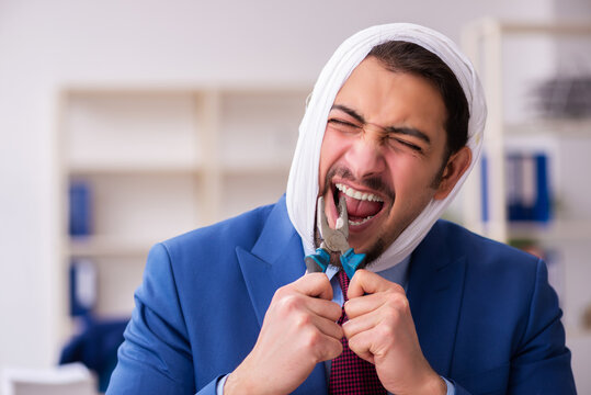 Young male employee suffering from toothache at workplace