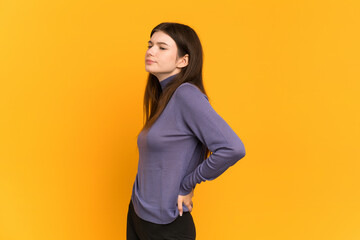 Young Ukrainian girl isolated on yellow background suffering from backache for having made an effort