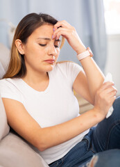 Upset latino woman crying while sitting on a sofa in a room