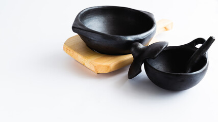 black clay dishes in a wooden basket, very traditional to serve food, used in Colombia. on white background