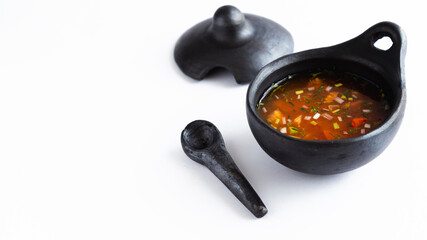 chili in black clay dish very typical of Colombian culture, White background