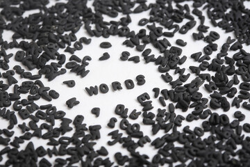Grupo de Letras negras dispersas sobre fondo Blanco. Foto Macro de letras negras. Palabra 