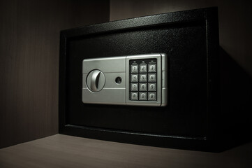 Small modern safe on shelf in dark. Small safe box close up in low key light