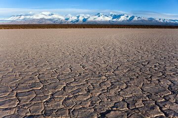 dry cracked earth in the desert and mountains background blue sky