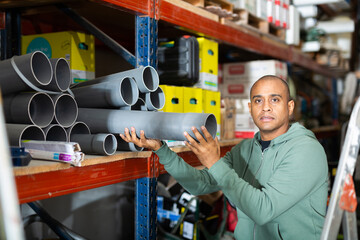 Craftsman selects plastic plumbing pipes in a hardware store