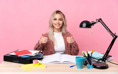 Young student woman working in a table giving a thumbs up gesture