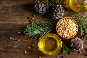 Pine nuts, oil and cedar cones on rustic wooden background
