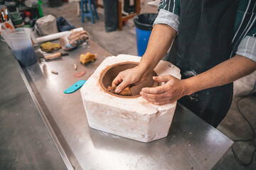 young adult potter molding with clay to make a piece of ceramic