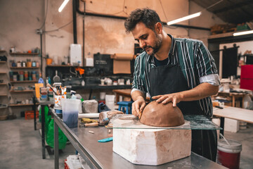 young adult potter molding with clay to make a piece of ceramic