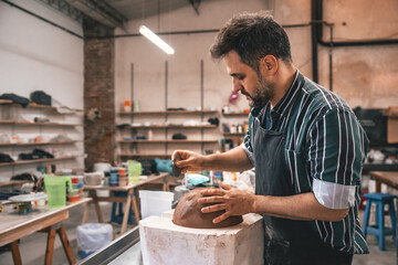 young adult potter molding with clay to make a piece of ceramic