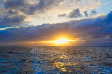 Obraz premium The sunlight appeared and disappeared from time to time between the clouds. The haze is very spectacular. The sunset seen from the boat. North Pacific Ocean, June, 2019.