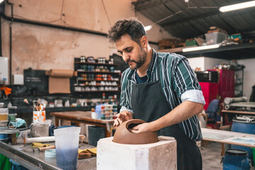 young adult potter molding with clay to make a piece of ceramic