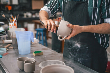young adult potter preparing some pieces of clay to put in the kiln
