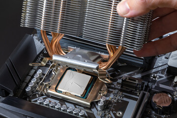 A technician installs an aluminum air-cooled heatsink on a desktop PC CPU. Air Cooler CPU. PC assembly and modernization