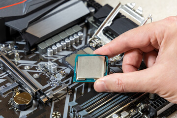 Installing the CPU into a socket on the motherboard. The technician holds the blank central...