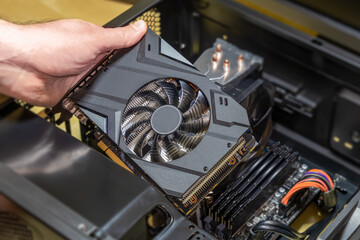 Installing a video card on the motherboard. The technician installs computer components in a open PC case. PC assembly and modernization