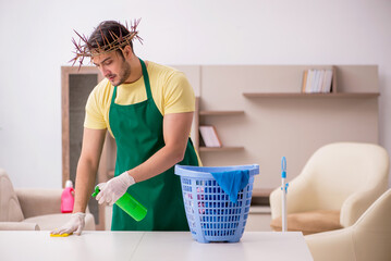 Young male contractor wearing prickly wreath on head cleaning th