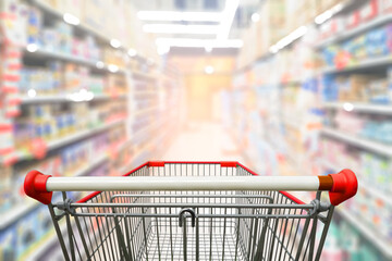 Supermarket aisle with empty red shopping cart. - obrazy, fototapety, plakaty