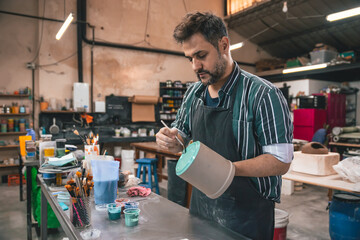 young adult potter painting pieces of clay