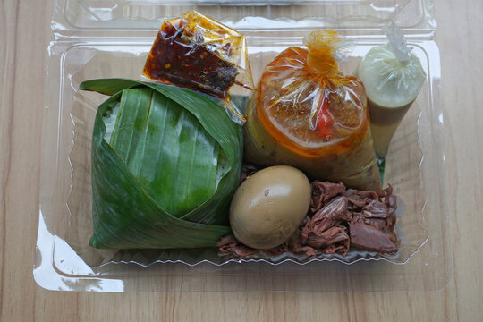Gudeg for take away lunch. Rice wrapped in banana leaves, jackfruit or gudeg vegetables, coconut milk sauce, chili sauce and eggs.  