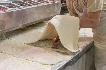baker's hand working with a dough rolling machine