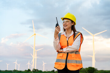 female engineer using walkie talkie to checking system against wind turbine farm