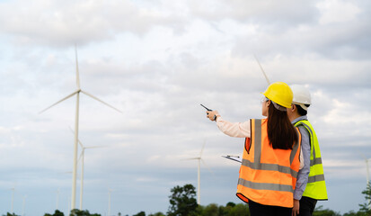 engineer team working with report in clipboard against wind turbine farm