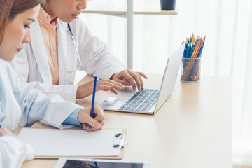 Two asian women doctors discuss meeting doctor's office medical clinic using laptop consulting patient disease. Asian medical lab young women talking together discussing healthcare assistance teamwork