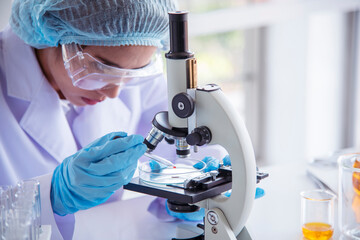 Woman scientist in lab look at science microscope medical test and research biology chemistry....