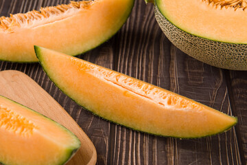 close-up of cut fresh Hami melon fruit on wooden background.