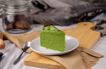 Japanese matcha green tea cake topping with chocolate past on white plate.