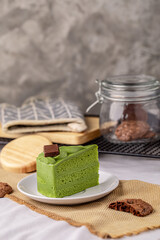 Japanese matcha green tea cake topping with chocolate past on white plate with brownie.