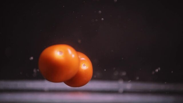 Cherry Tomatoes falling in slow motion, fruits floating on top of each other on black background in 4k