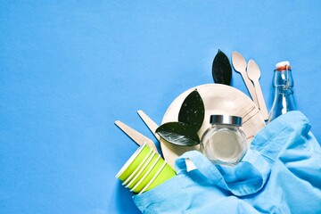 Plastic free. Set with blue cotton bag, glass jars, green leaves and wood tableware on a blue background. Top view. Zero waste, eco friendly concept. Flat lay. Copy space