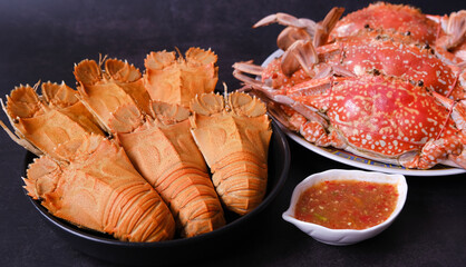 Big steamed crabs and crawfish (crayfish)  in a dish with spicy sauce isolated on black background. 