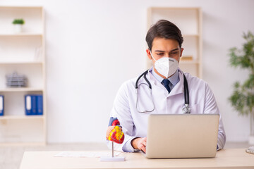 Young male doctor cardiologist working in the clinic during pand