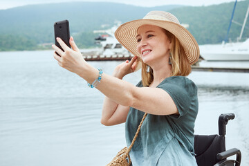 Portrait of a woman in a hat makes a selfie against the backdrop of a seascape