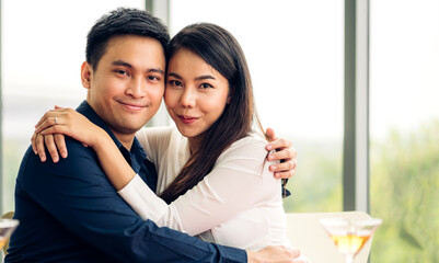 Romantic young happy asian couple relax hugging celebrate together look at camera in the restaurant